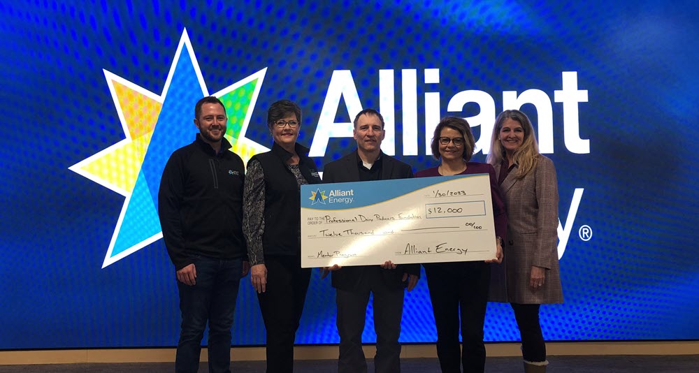 people holding a big check in front of an Alliant Energy logo