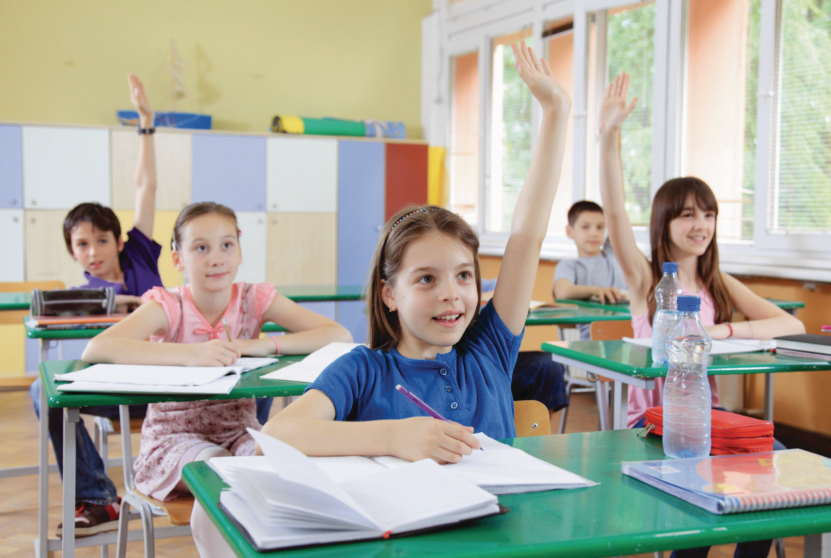 Elementary school students raising hands