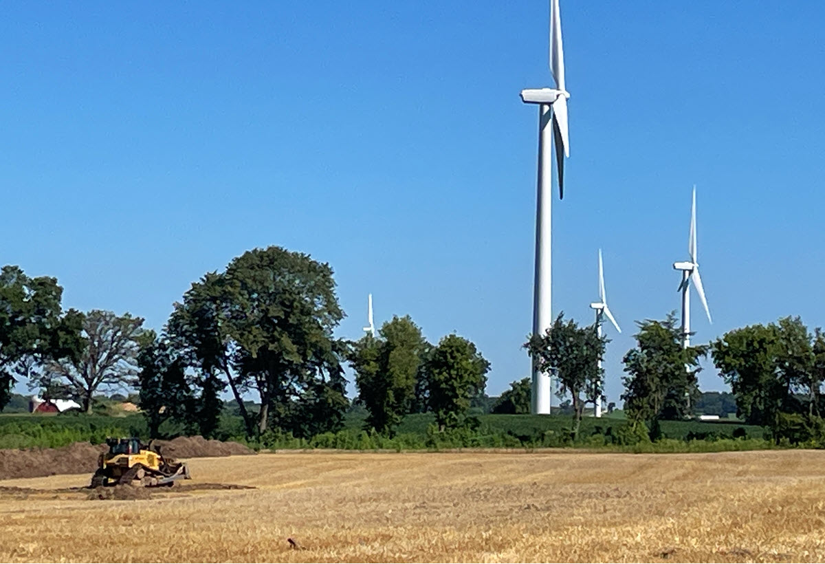A row of wind turbines sit just beyond the construction site for the Springfield Solar Project. 