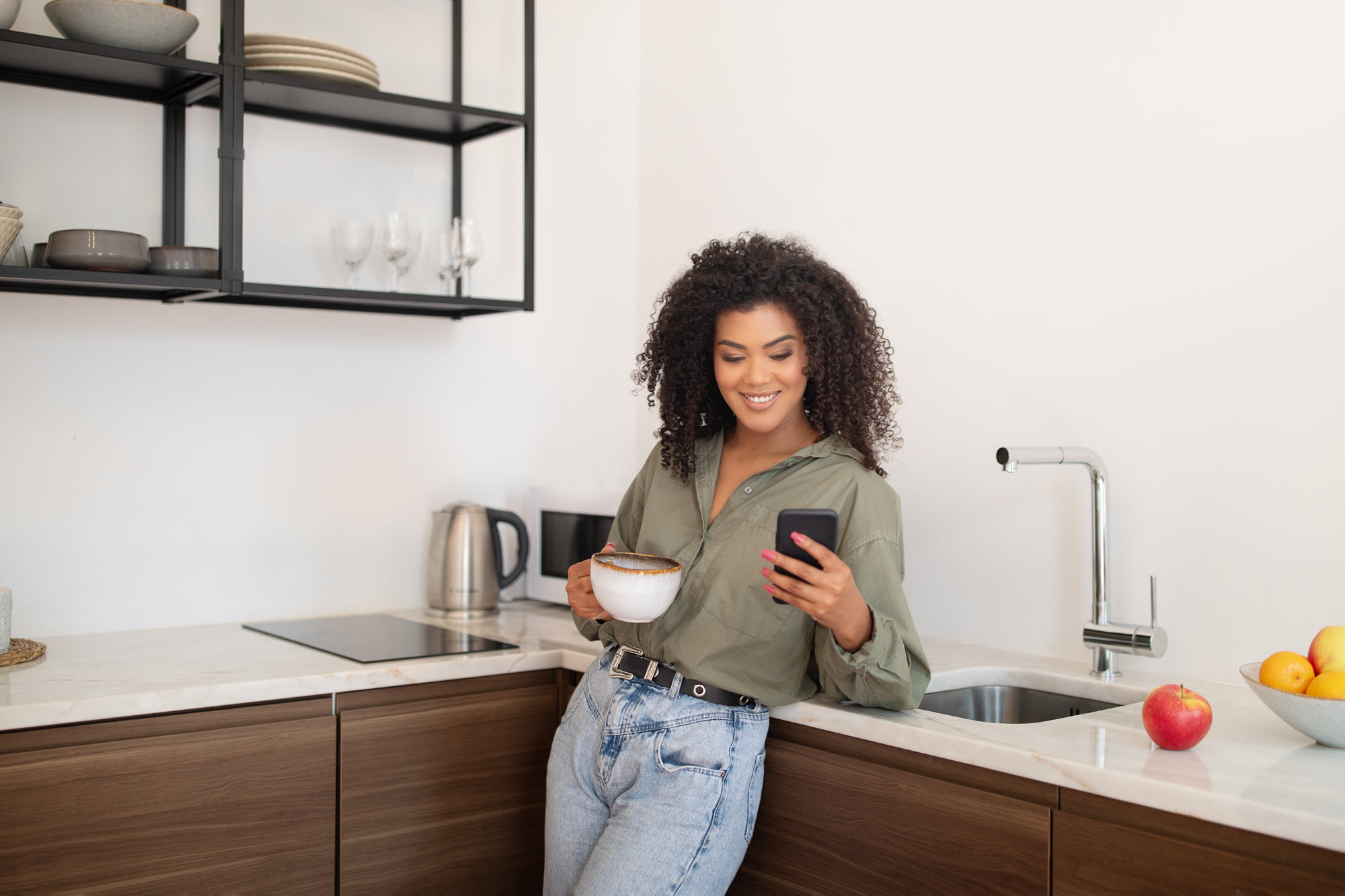 happy woman in her kitchen, looking at her phone