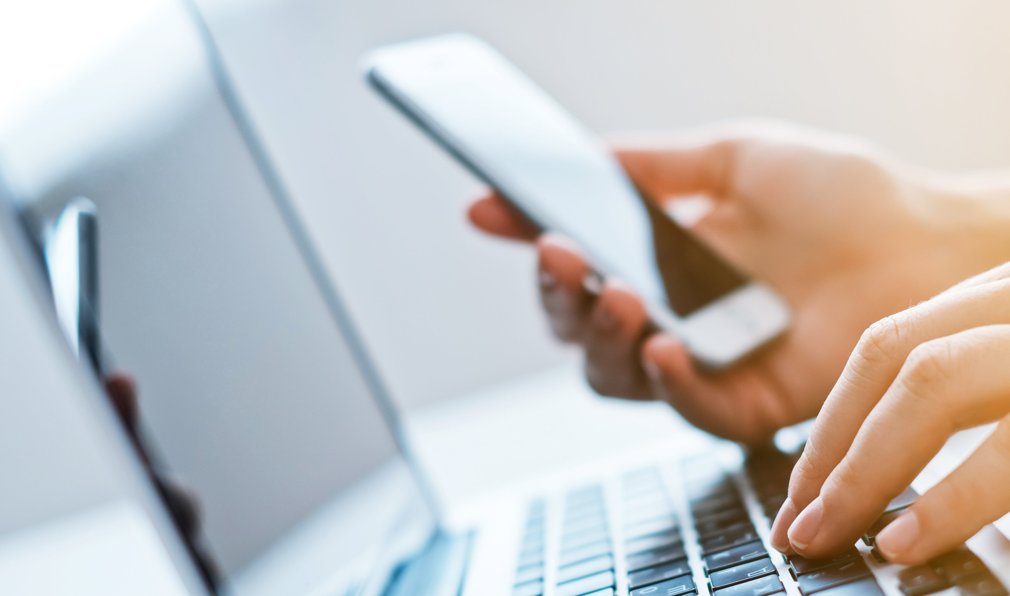 Person looking at phone and typing on computer