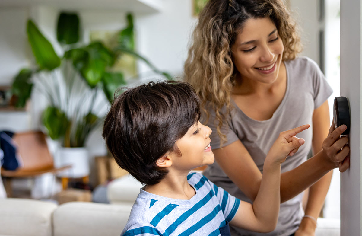 mother and son looking at a smart thermostat