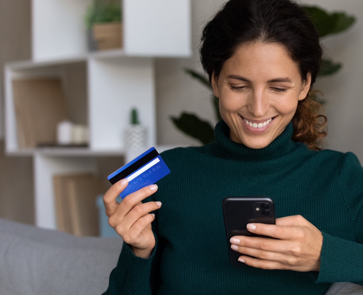 smiling woman holding a credit card and a phone