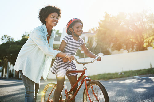 Mom helping her daughter ride a bike