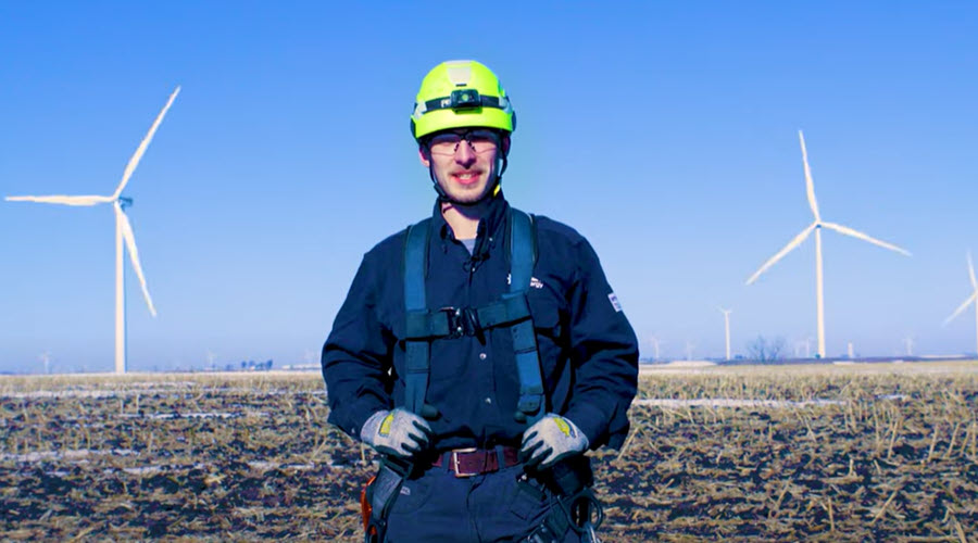 video screenshot of a man standing near a wind farm