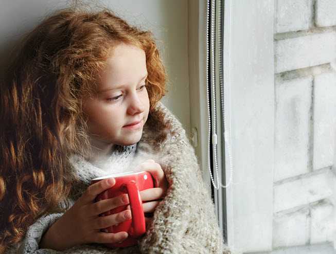 girl in front of window with hot cocoa