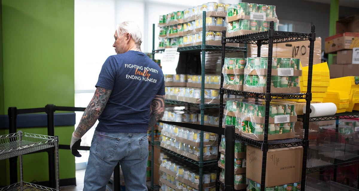 volunteer standing next to racks of canned goods
