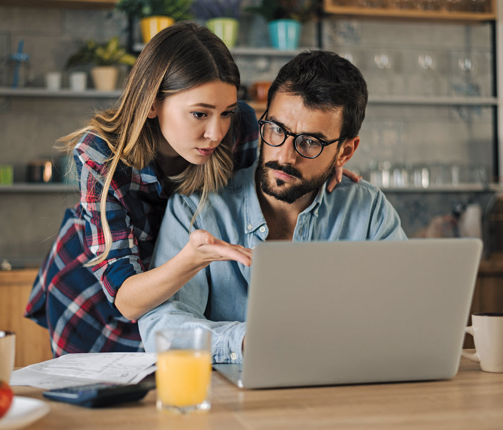 concerned-looking couple looking at a laptop