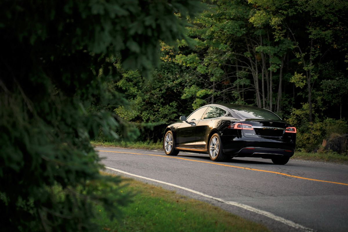 Electric vehicle driving on a tree-lined street. 