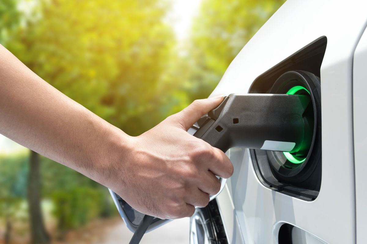 A hand plugging in an electric vehicle charger into their car