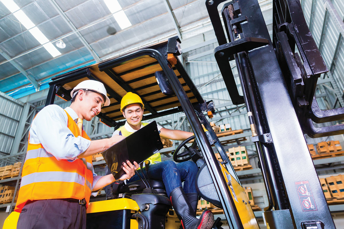 two employees talking near a forklift in a warehouse