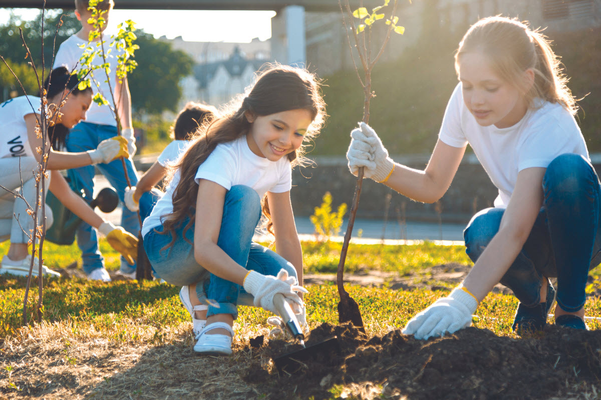 Two kids working together to plant a tree