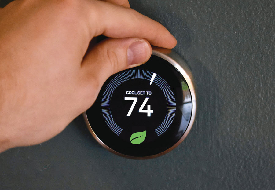 Hand adjusting smart thermostat to 74 degrees Fahrenheit.