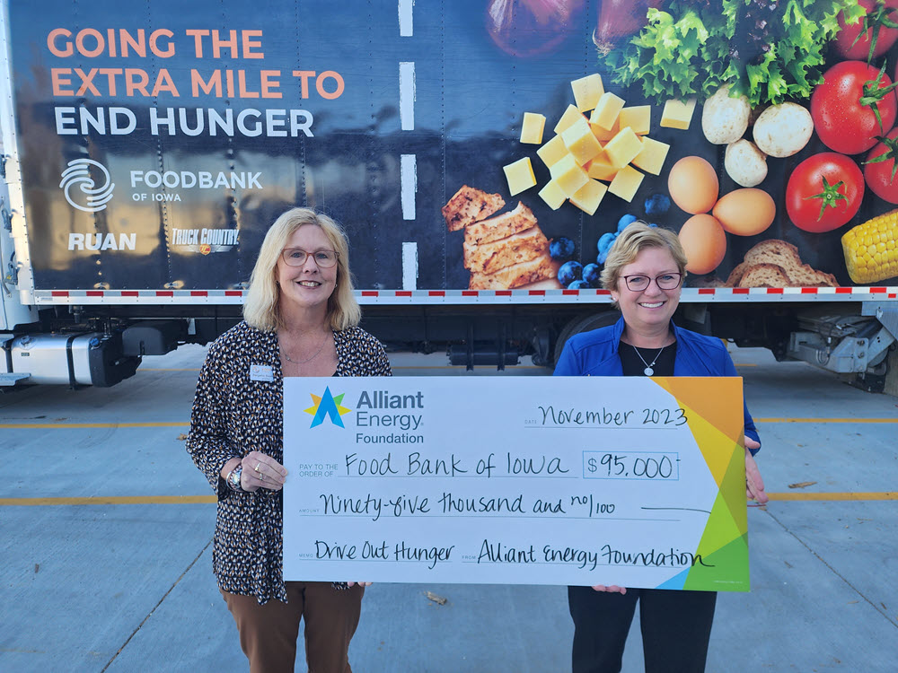 two people holding a large check in front of a food bank truck