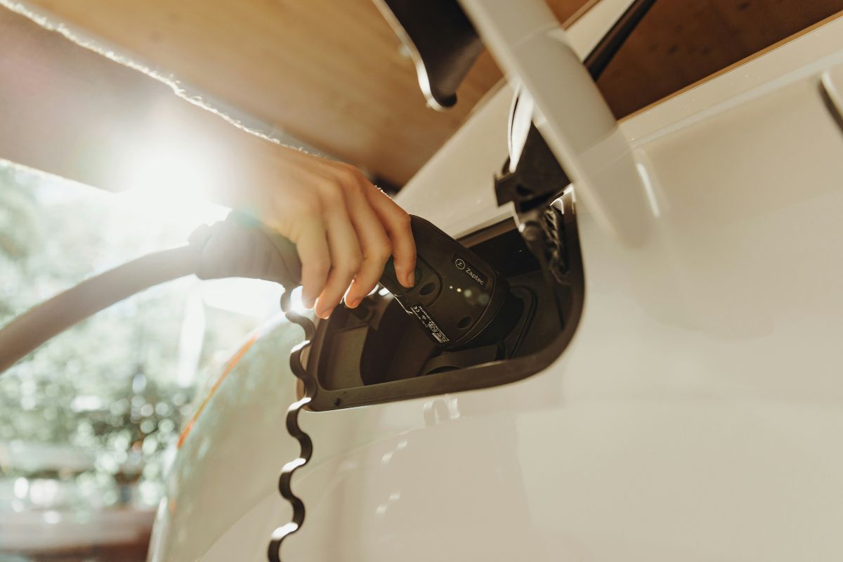 Person plugging an electric vehicle charger into an electric vehicle.