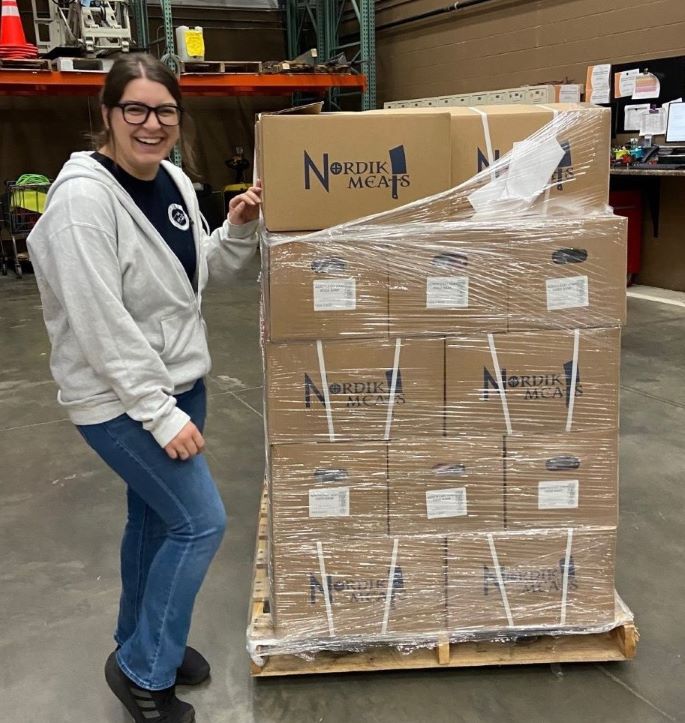 Food bank employee with pallet of protein.