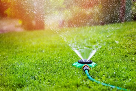 Lawn sprinkler watering a grass yard. 