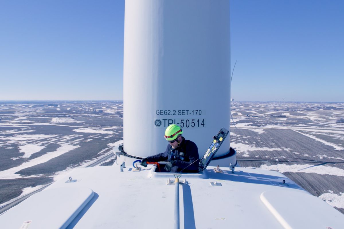 Wind technician doing electrical work on the top of a turbine.