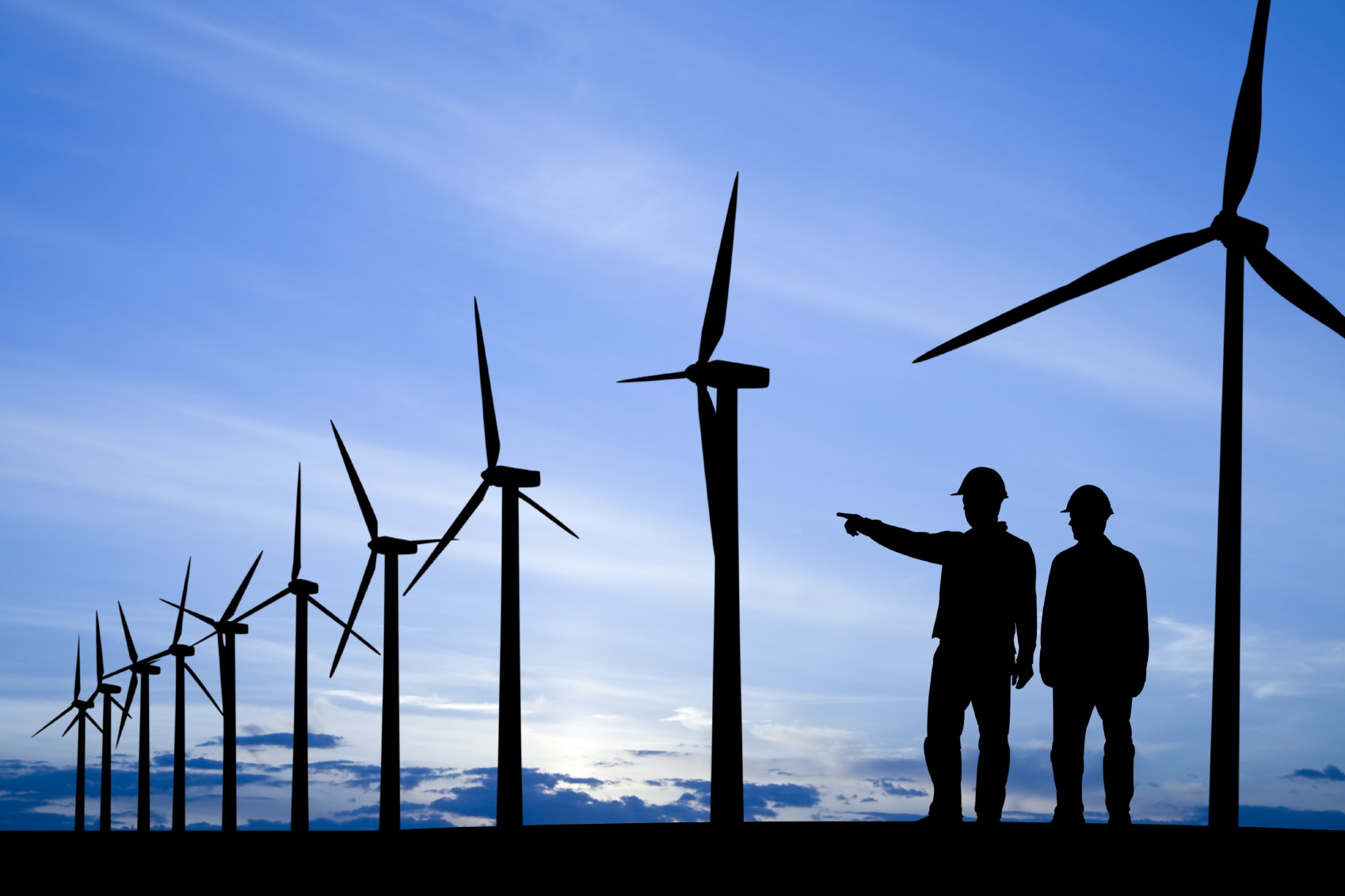 Two men standing near wind farm at dusk