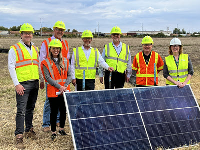group of people standing with a solar panel