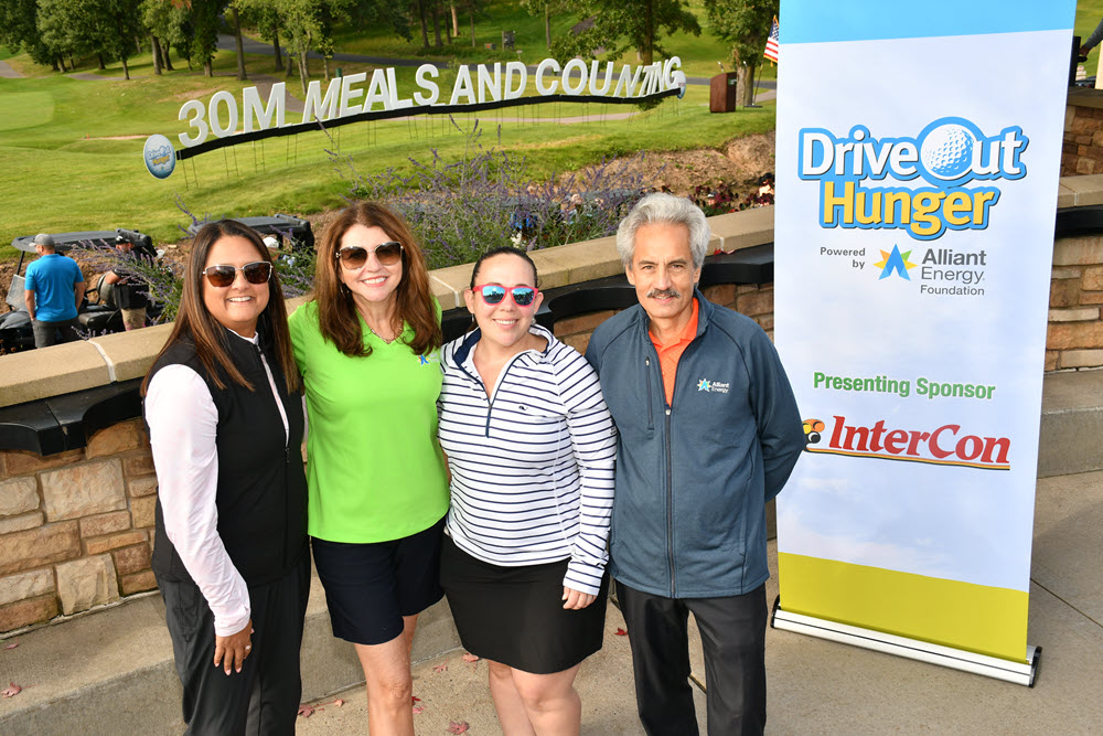 Four people next to a Drive Out Hunger sign