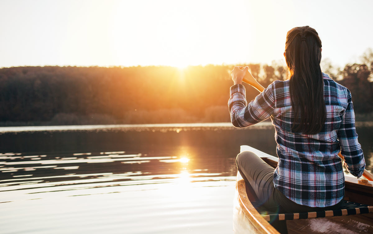 woman in a canoe on a lake at sunset