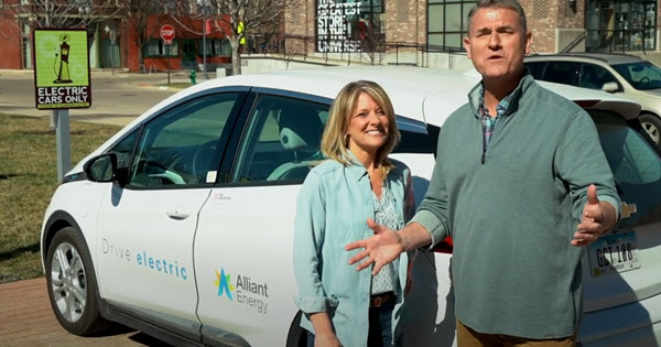 Pete and Megan from PowerHouse standing in front of an EV