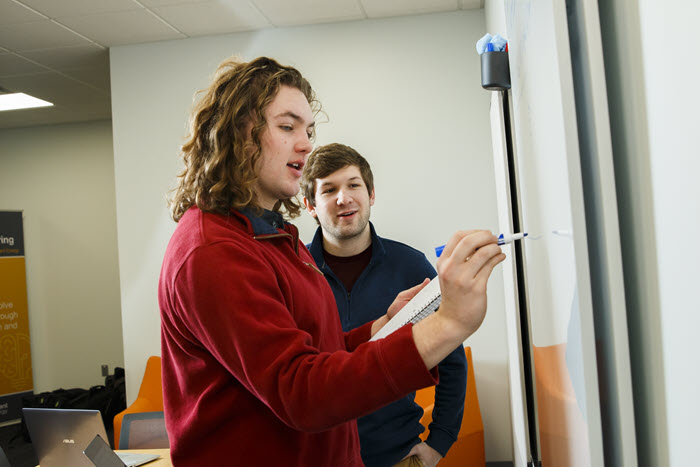Two people collaborating near a whiteboard