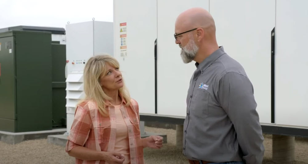 woman and man talking in front of a large battery storage system