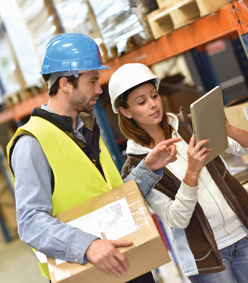 two employees in a warehouse looking at a tablet
