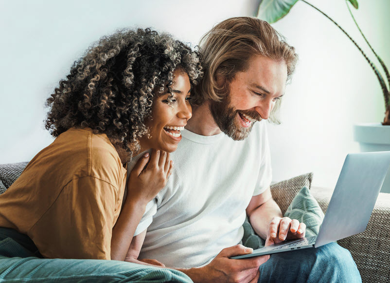 happy couple on couch with laptop