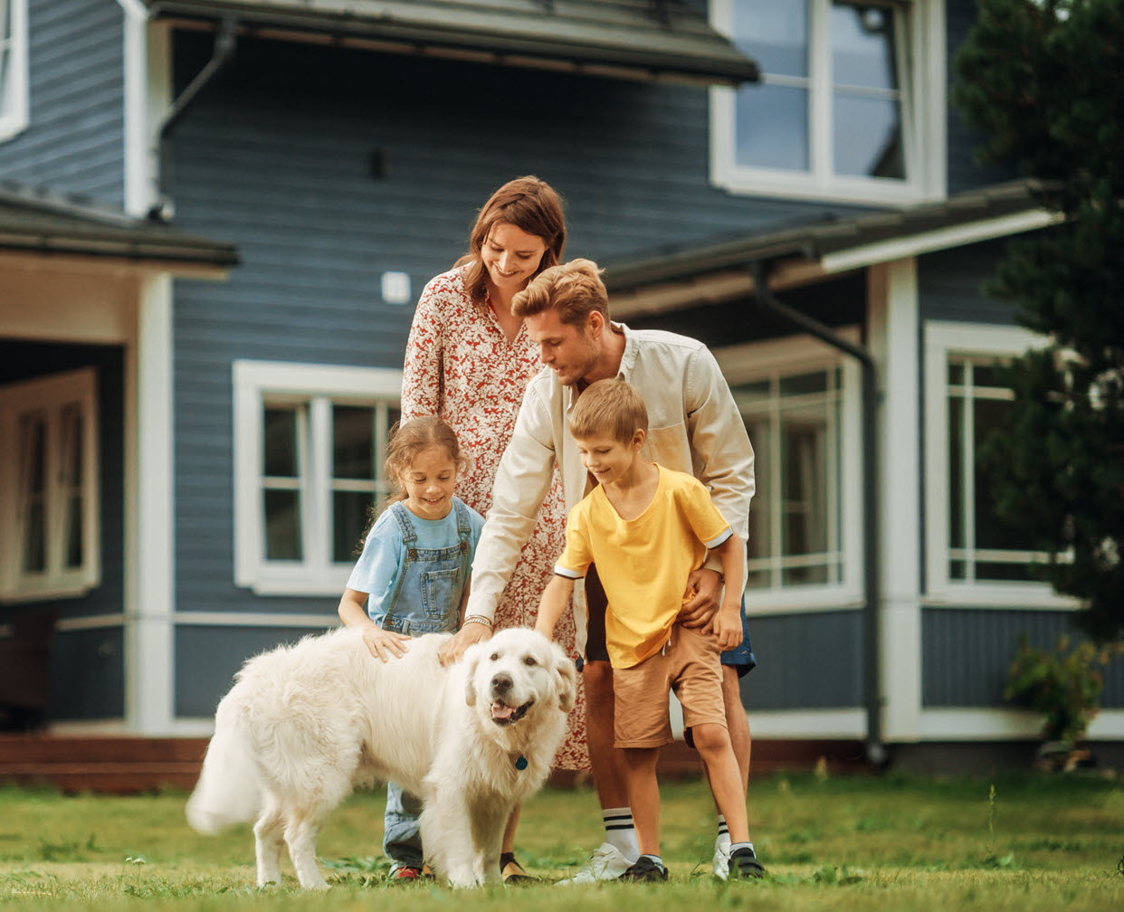 family playing with a dog in front of a house
