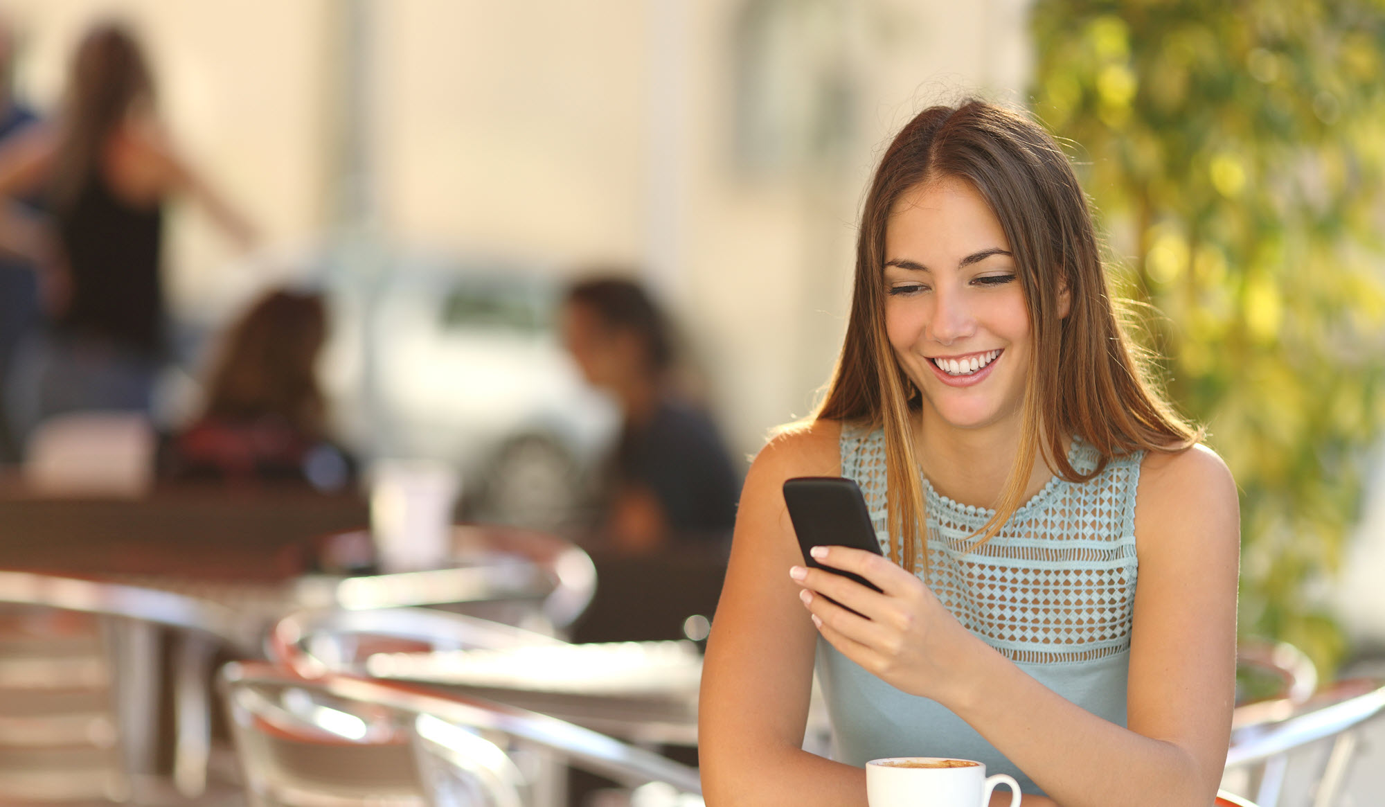 young woman at a cafe looking at a phone