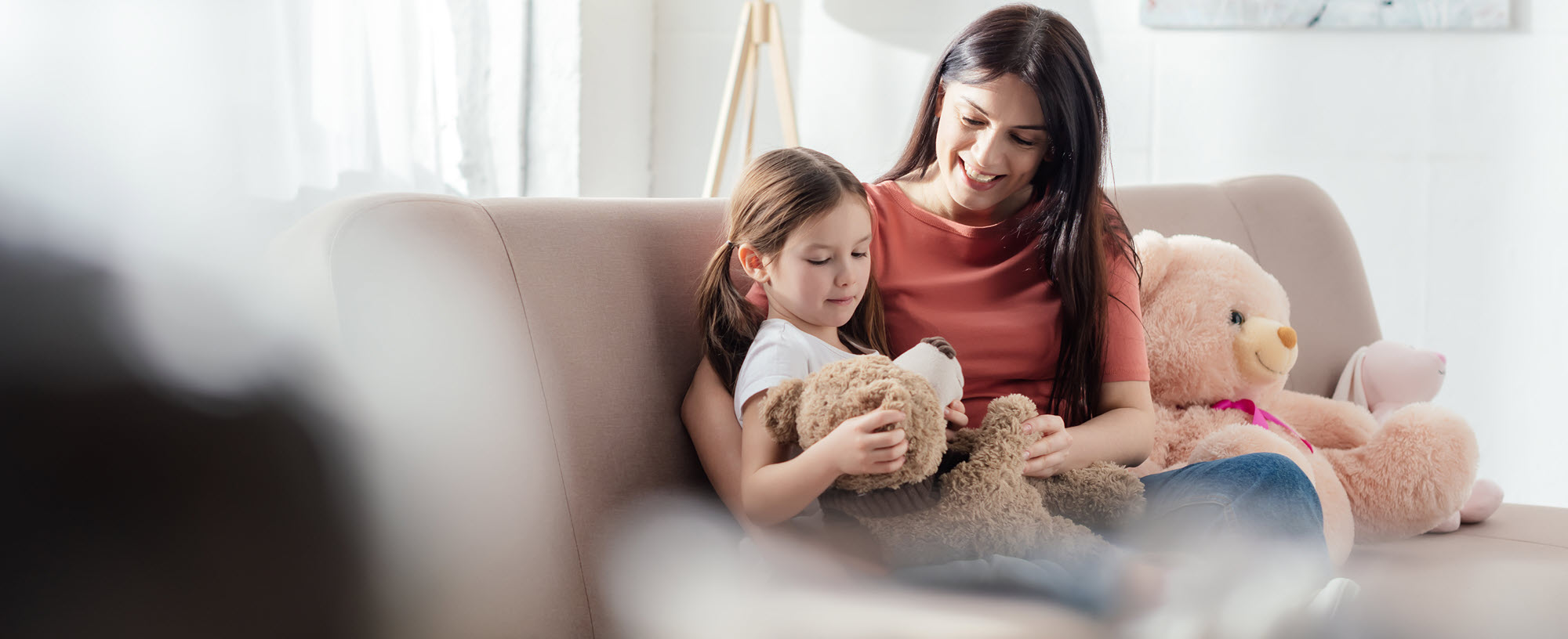 mom and daughter on a couch with teddy bears