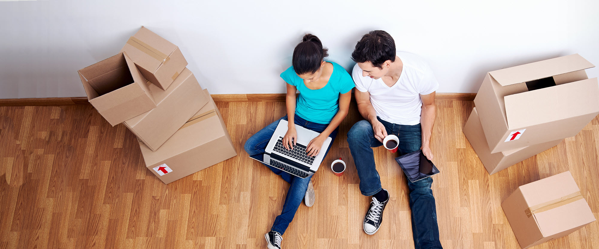Couple on a laptop with moving boxes nearby
