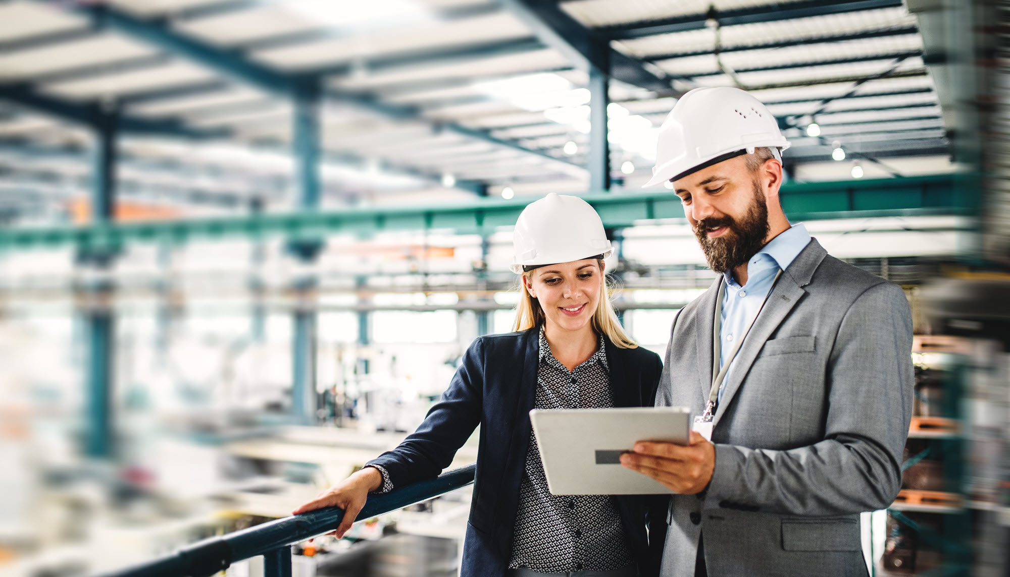 two people in hard hats standing in a factory