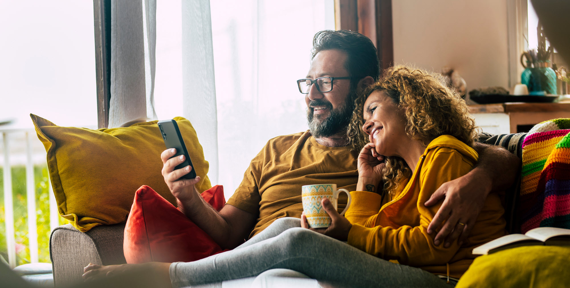 couple cuddling on a couch looking at a phone