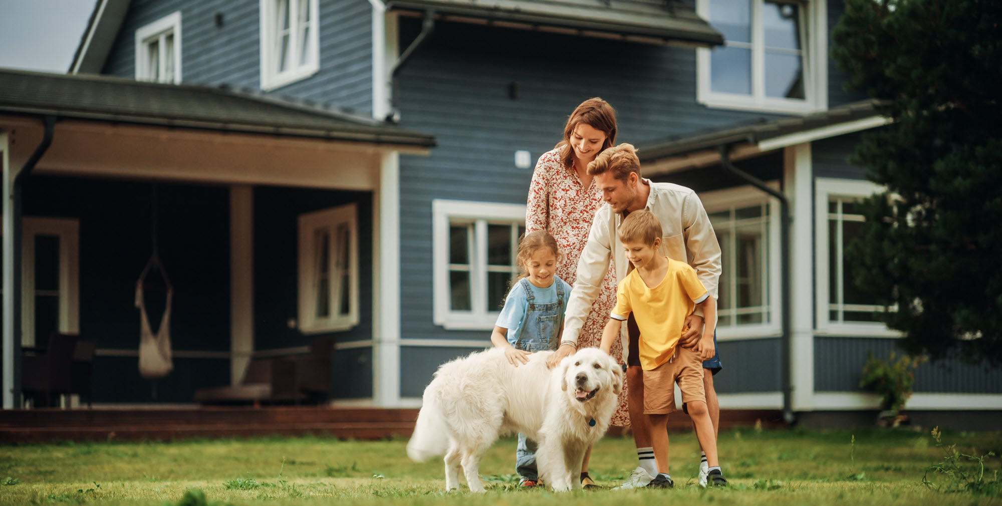 family outside of their house playing with their dog