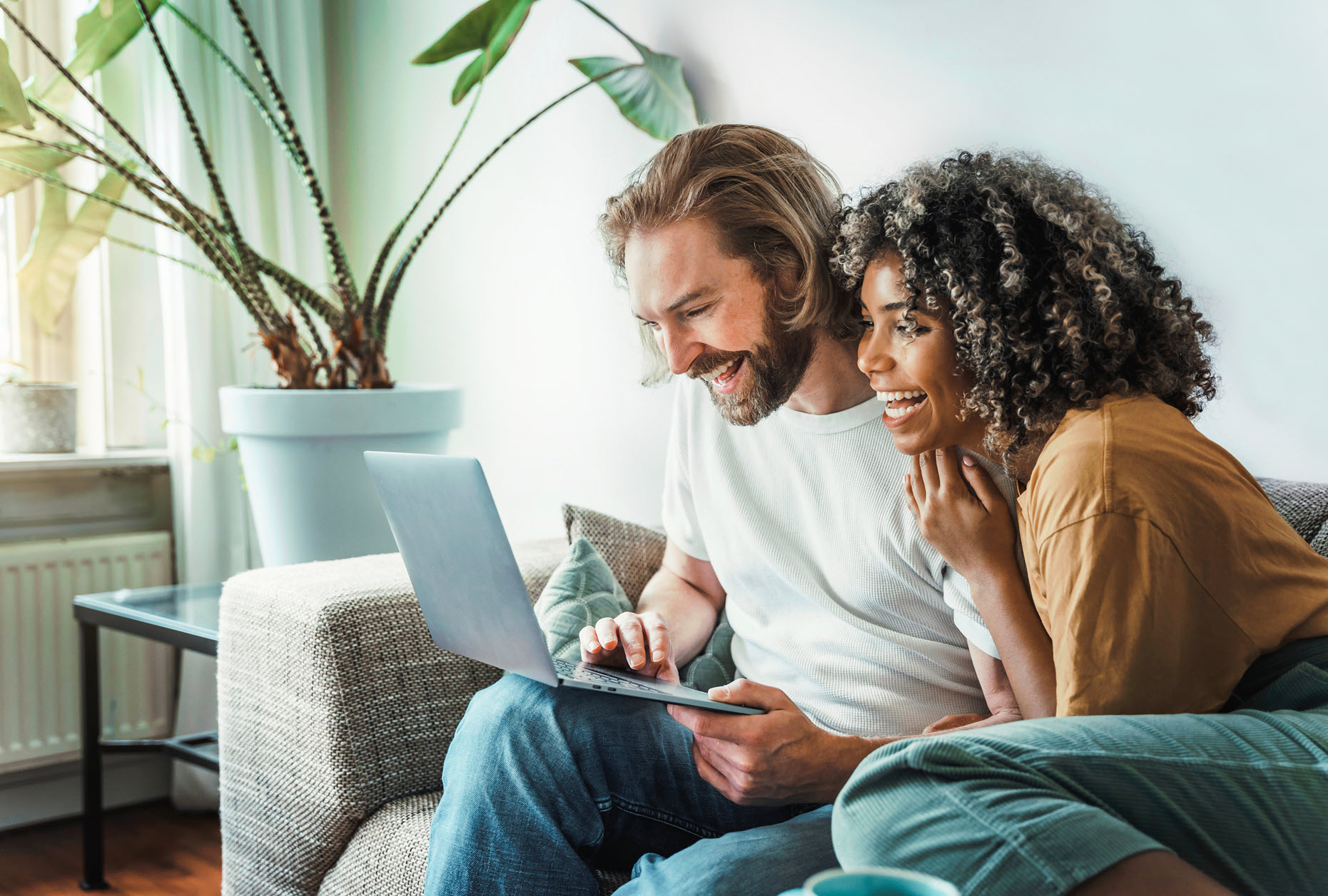 happy couple on a couch looking at a laptop